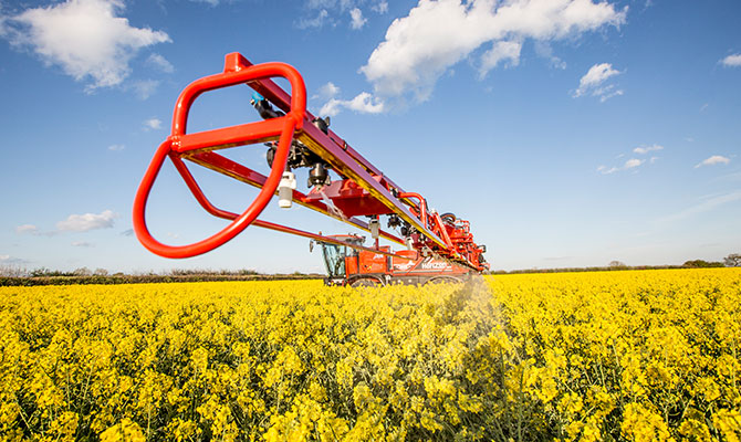 Up close to a fertiliser sprayer driving through Oilseed rape field