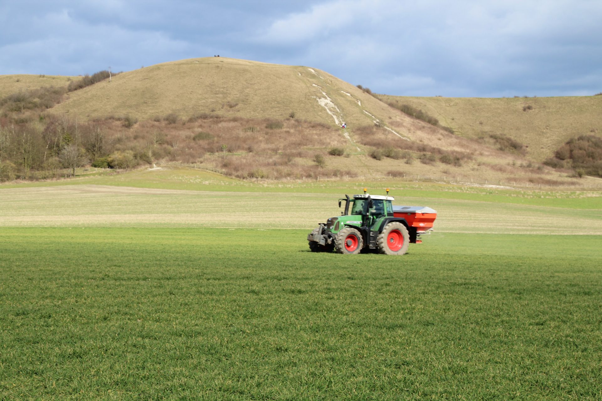 Tractor driving across field spraying fertiliser